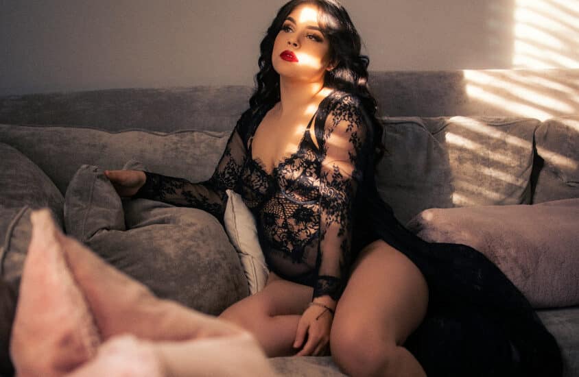 Runde Frau sitzt alleine auf einem Sofa im Swingerclub